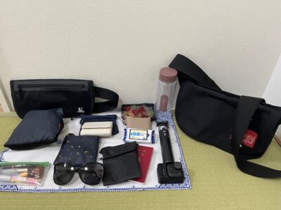 旅先で持ち歩いているバッグの中身一式。財布やサングラス、ガジェット類を並べた様子