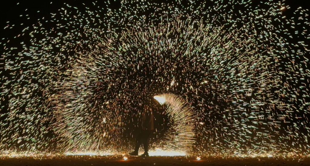 アガファイ砂漠ツアーのファイヤーショー。夜の砂漠で火花が大きく広がるパフォーマンス