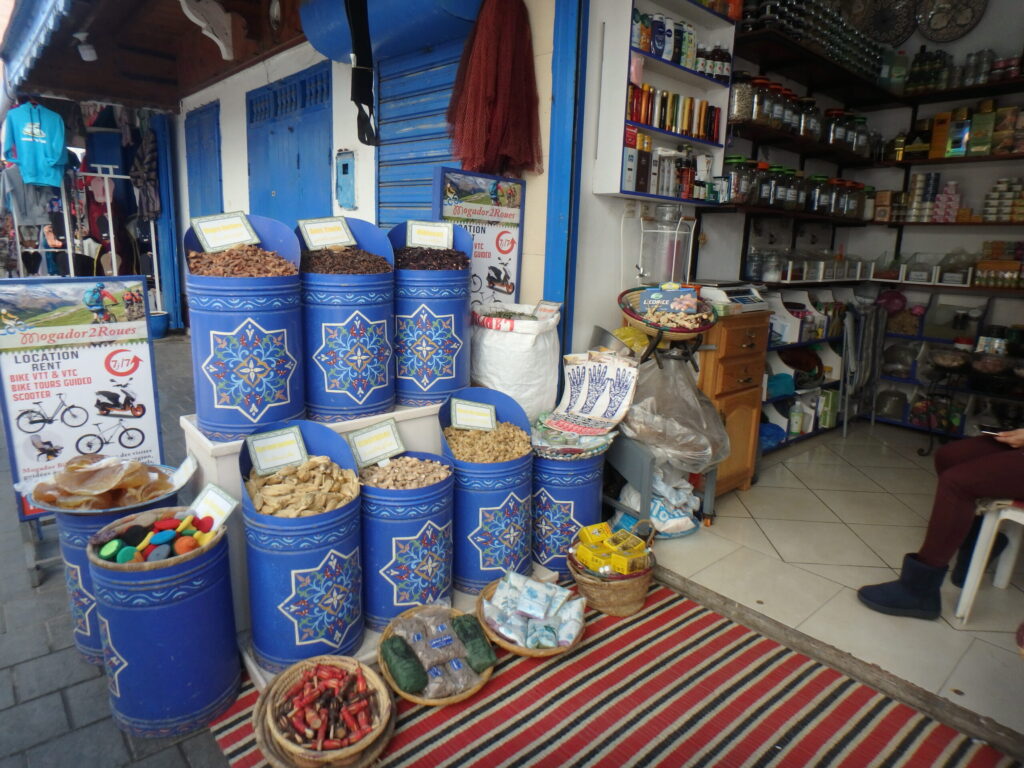 エッサウィラのメディナにあるスパイスとナッツの専門店。青い装飾バケツに並ぶ乾燥食材と店内の様子